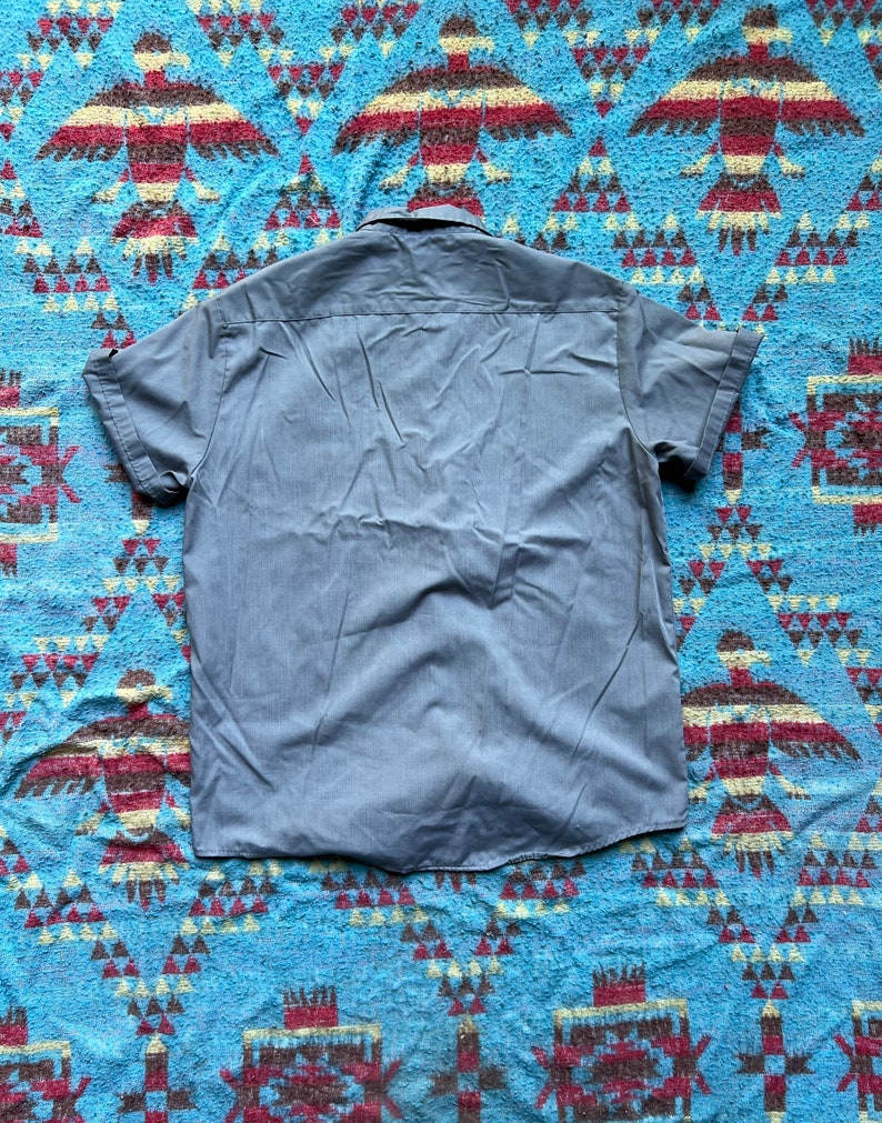 以下が含まれることがあります： 薄い青色のボタンダウンの半袖シャツ。尖った襟が特徴です。