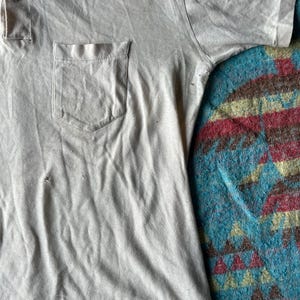 May include: A light gray short-sleeved collared shirt with a single button closure and a patch pocket on the left side.