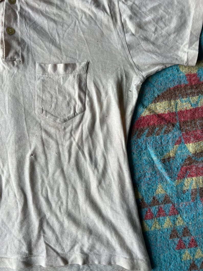 May include: A light gray short-sleeved collared shirt with a single button closure and a patch pocket on the left side.