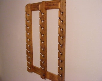 May include: A wooden wall-mounted rack with multiple slots for storing items. The rack is made of natural wood and has a light brown finish.