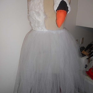 Pu&ograve; includere: Un tut&ugrave; di tulle bianco con un top da costume di cigno bianco e una testa di cigno con un becco arancione.