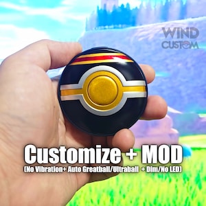 Pode incluir: Uma Poké Ball preta e dourada com detalhes vermelhos e amarelos. A Poké Ball está sendo segurada em uma mão. O texto "WIND CUSTOM" está no canto superior direito da imagem. O texto "Customize + MOD (No Vibration+ Auto Greatball/Ultraball + Dim/No LED)" está na parte inferior da imagem.