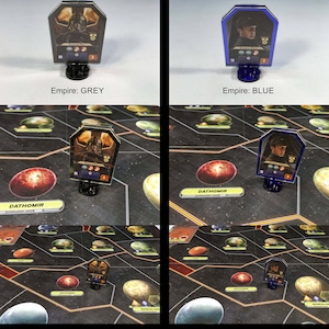 May include: Two Star Wars Rebellion game pieces, one with a grey base and one with a blue base. Both pieces feature a character from the Star Wars universe. The pieces are on a game board with a red planet in the background.