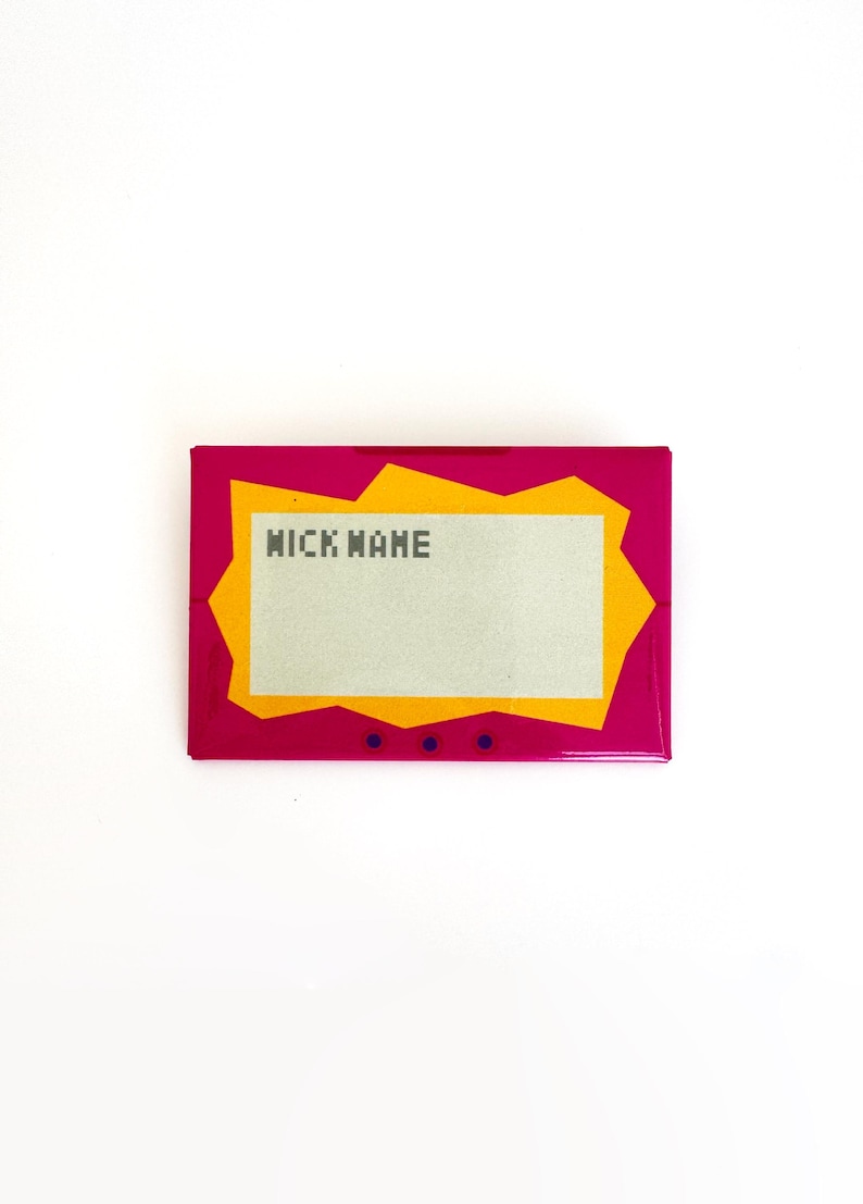 May include: A rectangular pin featuring a vibrant magenta border with a jagged orange inner frame surrounding a light gray center panel. The text "NICK NAME" is printed in a dark gray pixelated font on the upper left side of the gray panel.