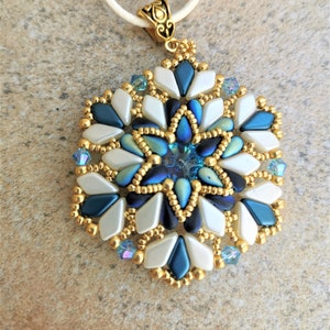 May include: A gold and blue beaded pendant necklace with a white cord. The pendant is a starburst design with a blue crystal in the center.