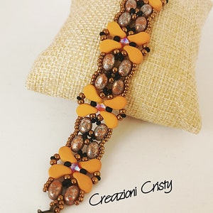 May include: A beaded bracelet with orange, brown, and silver beads in a floral pattern. The bracelet has a clasp closure and is displayed on a brown fabric surface. The text "Creazioni Cristy" is visible in the lower right corner of the image.
