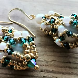 May include: A pair of gold earrings with white and green beads. The earrings are made with small gold beads, white pearls, and green crystals.
