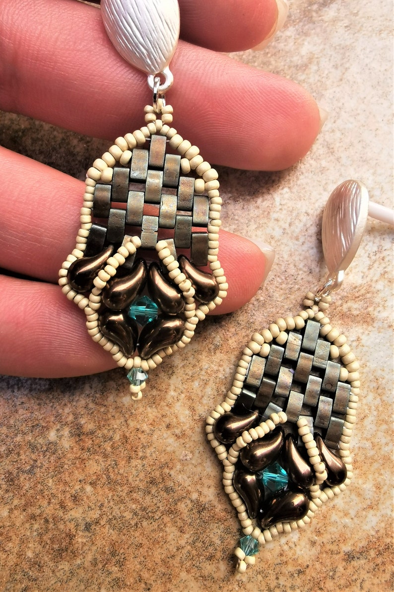 May include: A pair of dangle earrings featuring a woven metal design, brown and cream coloured beads, and a teal gemstone accent.