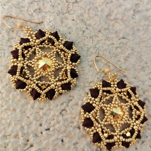 May include: A pair of gold and burgundy beaded earrings with a starburst design and a gold crystal in the center.