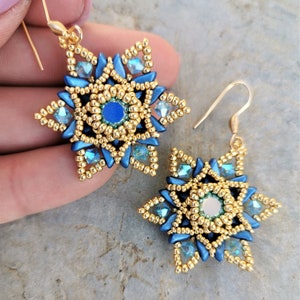 May include: A pair of gold and blue star-shaped earrings with a beaded design. The earrings have a gold hook closure.