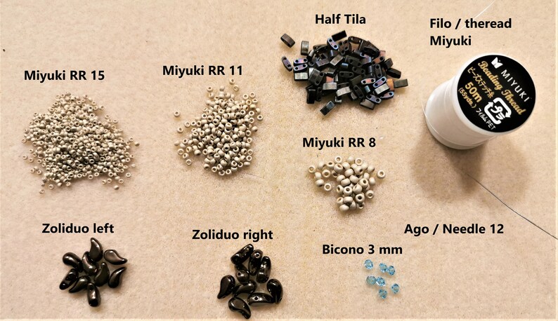 May include: Assortment of beads and beading supplies for jewellery making, including white seed beads, black teardrop beads, blue bicone beads, silver half tila beads, and a spool of white beading thread.