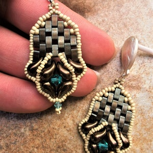 May include: A pair of dangle earrings featuring a woven metal design, brown and cream coloured beads, and teal blue crystals.