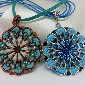 以下が含まれることがあります： 丸いペンダントが付いたビーズネックレスが2本。左側のペンダントは銅とターコイズ、右側のペンダントは銀と青です。
