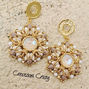 May include: A pair of gold and beige beaded earrings with a starburst design and iridescent crystals in the center. The earrings are attached to gold hoops.