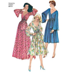 May include: A vintage Simplicity sewing pattern for a wrap dress with long sleeves and a V-neckline. The pattern shows three different styles of the dress, one in pink with white polka dots, one in a floral print, and one in blue.