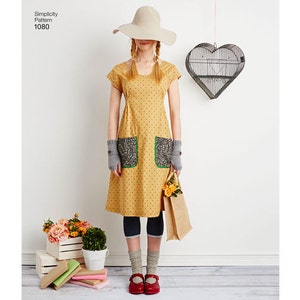 May include: A mustard yellow dress with black polka dots, featuring two front pockets with a floral pattern and green trim. The dress is paired with grey fingerless gloves, red shoes, and a wide-brimmed hat. A paper bag with flowers is held.