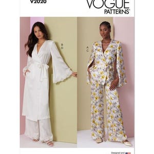 May include: Vogue Patterns V2020. Two women model different outfits. One wears a white wrap robe and matching pants. The other wears a floral print jacket with cape sleeves, a matching belt, and wide-leg pants. The Vogue Patterns logo is visible.