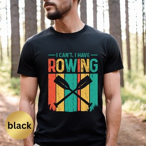 May include: Black t-shirt with a vintage-style graphic that says "I can't. I have rowing" with crossed oars and a striped background.
