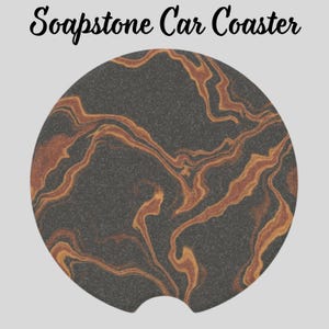 May include: A round soapstone car coaster with a dark gray background and swirling patterns in shades of brown and orange. The coaster has a small notch on one side for easy removal from a car cup holder. The text "Soapstone Car Coaster" is at the top.