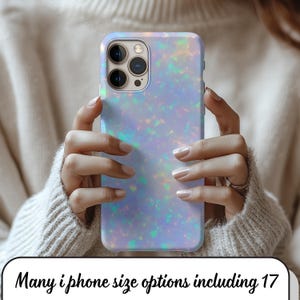 以下が含まれることがあります： 光沢のある仕上がりの、ライトブルーのイリデセントiPhoneケース。ケースにはマルチカメラの切り抜きがあり、人が持っています。下部のテキストは「Many iPhone size options including 17」と書かれています。