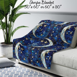May include: A blue sherpa blanket with a mosaic design featuring crescent moons and stars. The blanket is draped over a white couch. Available in 50" x 60" or 60" x 80" sizes.