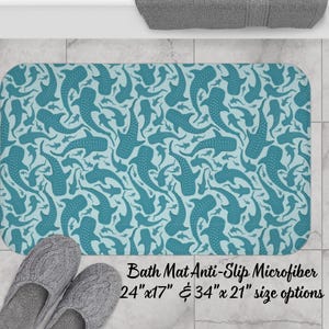 Könnte beinhalten: Ein rechteckiger Badteppich mit einem sich wiederholenden Muster aus teal Walhai-Illustrationen auf hellblauem Hintergrund. Der Teppich ist aus Mikrofaser und in den Größen 61 cm x 43 cm und 86 cm x 53 cm erhältlich. Der Text "Bath Mat Anti-Slip Microfiber" ist aufgedruckt.