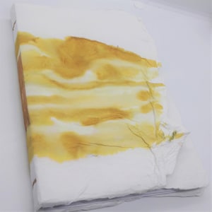 Op de afbeelding: Een handgemaakt dagboek met een witte omslag en gele aquarel accenten. De omslag is gemaakt van gestructureerd papier en heeft een rustieke, handgemaakte uitstraling.