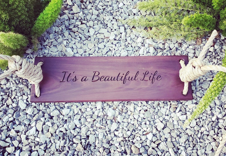 Puede incluir: Un columpio de madera con cuerda y las palabras "It's a Beautiful Life" grabadas en el asiento.