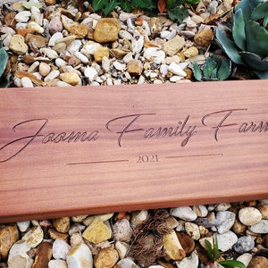 Puede incluir: Un columpio de madera con asas de cuerda, grabado con el texto "Joama Family Farm 2021".