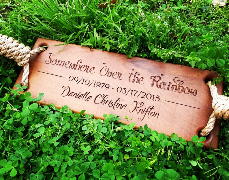 Puede incluir: Un columpio de madera con asas de cuerda, grabado con el texto "Somewhere Over the Rainbow", las fechas "09/10/1979 - 03/17/2015", y el nombre "Danielle Christine Knifton".