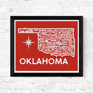 Puede incluir: Un mapa de Oklahoma en tipografía roja y blanca. El nombre del estado está escrito en letras blancas grandes en la parte inferior del mapa. El mapa está rodeado por un marco negro. El texto en el mapa incluye el lema del estado "Labor Omnia Vincit" y el apodo "The Sooner State".