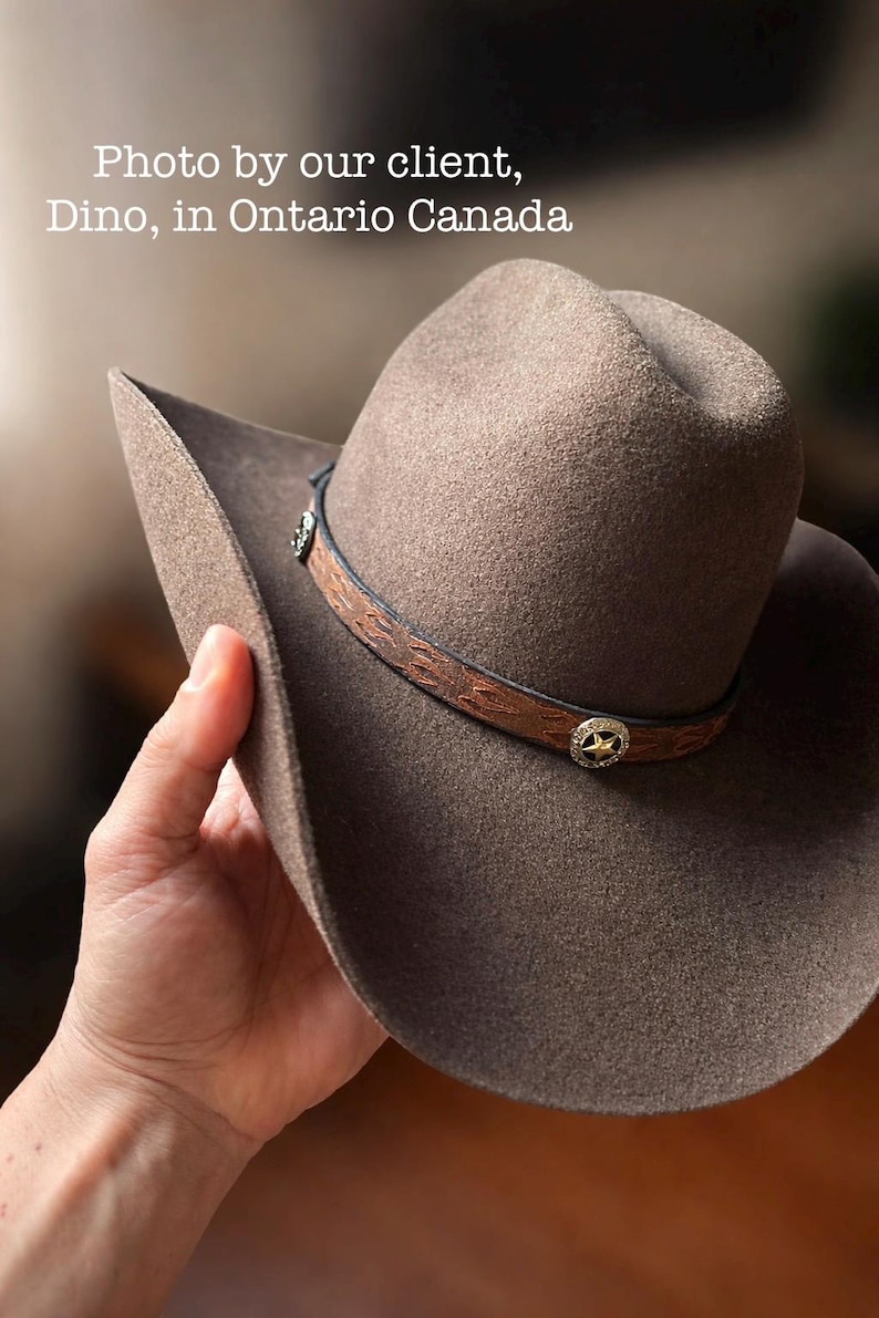 May include: A brown cowboy hat with a leather band featuring decorative stitching and silver-toned star-shaped accents. The hat has a wide brim and is made of a felt-like material. The text "Photo by our client, Dino, in Ontario Canada" is visible.