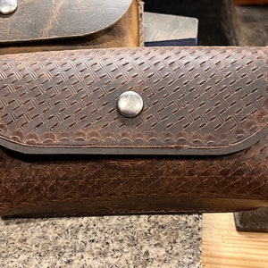 May include: A brown leather pouch with a woven pattern and a silver snap closure.