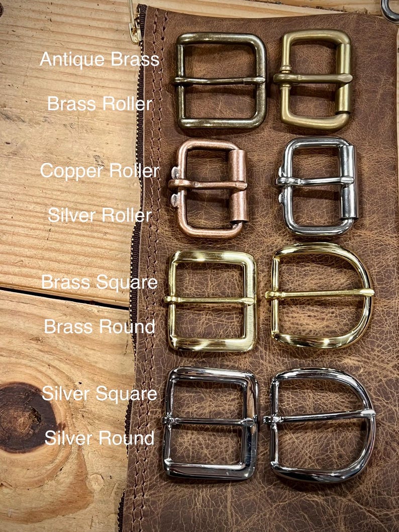 May include: A collection of eight metal belt buckles arranged in two columns. The set includes antique brass, brass roller, copper roller, silver roller, brass square, brass round, silver square, and silver round styles with labels for each.