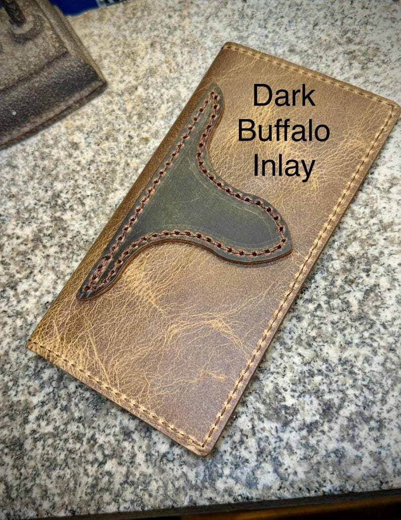 May include: A brown leather wallet with a dark green leather inlay. The inlay is shaped like a buffalo head and has the text "Dark Buffalo Inlay" on it.