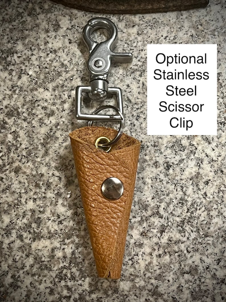 K&ouml;nnte beinhalten: Ein brauner Leder-Scherenhalter mit einem silbernen Clip und einem silbernen Knopf. Optional: Schere Clip aus Edelstahl.