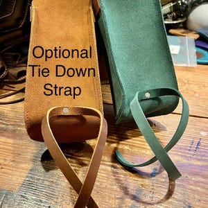 May include: Two leather pouches with optional tie down straps. The pouch on the left is brown and the pouch on the right is green.