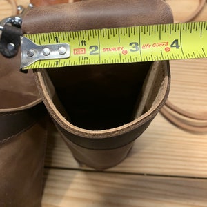 May include: A brown leather tool holder with a measuring tape across the top. The tape reads "25ft" and "Stanley Life Guard".