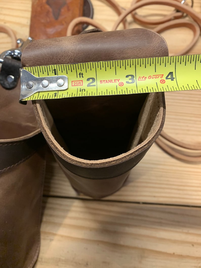 May include: A brown leather tool holder with a measuring tape across the top. The tape reads "25ft" and "Stanley Life Guard".