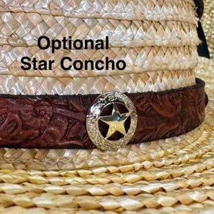 May include: Close-up of a straw cowboy hat with a brown leather band featuring a floral design. A silver star concho is attached to the band. The text "Optional Star Concho" is visible on the hat.