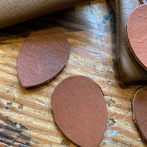 Peut inclure: Trois morceaux de cuir en forme de larme de couleur marron sur une surface en bois.