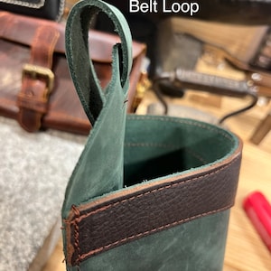 May include: A dark green leather pouch with a brown leather trim. The pouch has an optional belt loop.