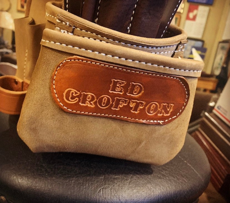 May include: A brown leather tool belt with a brown leather patch that says "ED CROFTON" in white lettering.