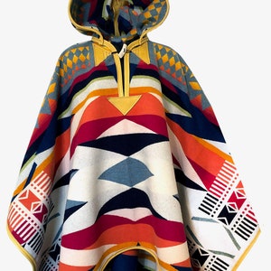 Könnte beinhalten: Ein farbenfroher Kapuzenponcho mit einem geometrischen Muster in Rot-, Orange-, Gelb-, Blau- und Weißtönen. Der Poncho hat einen Lederbesatz und einen Reißverschluss.
