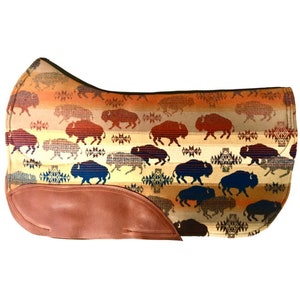 May include: A brown and tan saddle pad with a pattern of blue and red buffalo silhouettes. The saddle pad has a brown leather trim.