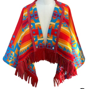 Puede incluir: Un poncho rojo, naranja, amarillo, azul y blanco con estampado, con ribete de cuero y flecos. El poncho tiene un cierre de botón.