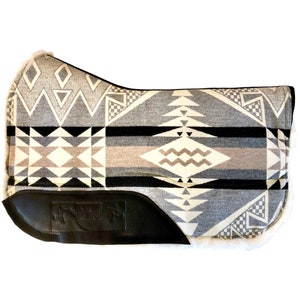 Peut inclure: Un tapis de selle gris et blanc avec un motif géométrique et une bordure en cuir noir. Le tapis a une bordure en peau de mouton blanche.