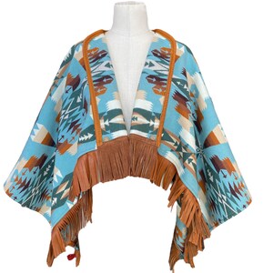 May include: A blue and brown patterned poncho with fringe trim. The poncho is made of a soft, woven fabric and has a geometric design.