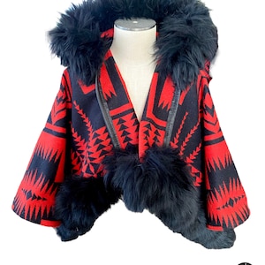May include: A red and black patterned hooded cape with a black faux fur trim and pom-poms.
