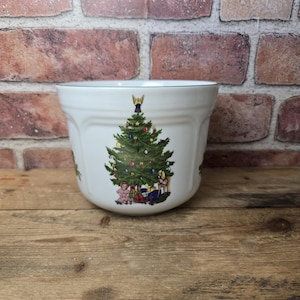 May include: White ceramic bowl with a Christmas tree design. The tree is decorated with ornaments and topped with a gold star. Presents are at the base of the tree. The bowl has a green trim around the rim.
